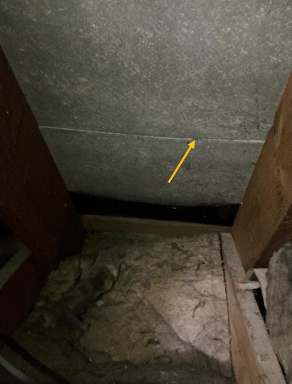 Asbestcementen onderdakplaat zichtbaar tussen de dakconstructie