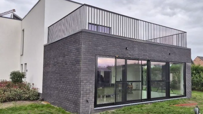 Afgewerkte aanbouw met grote glaspartij en terras